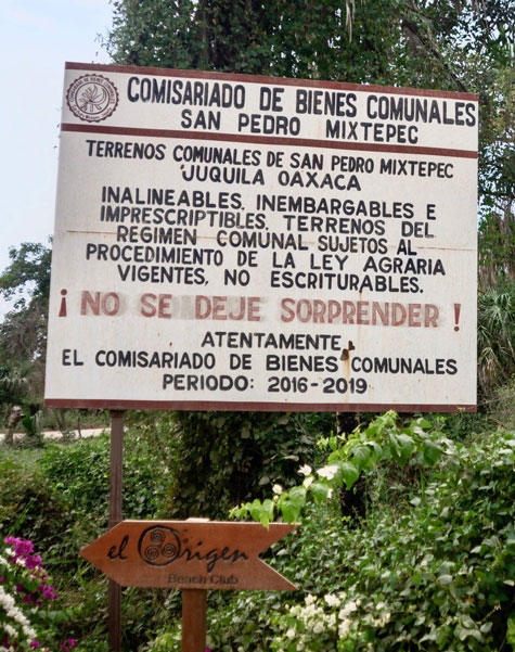 Aviso en la carretera de Bienes Comunales de San Pedro Mixtepec para los que piensan comprar terrenos en Palmarito. Dice que los terrenos no se pueden comprar con escritura porque son parte de la tierra comunal de San Pedro y están sujetos a la ley agraria.